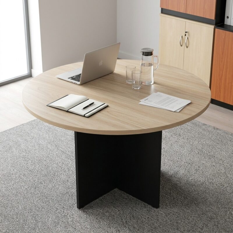 Modern Circular Executive Meeting Table with light oak round tabletop and black cross-panel base in a bright corporate office setting.