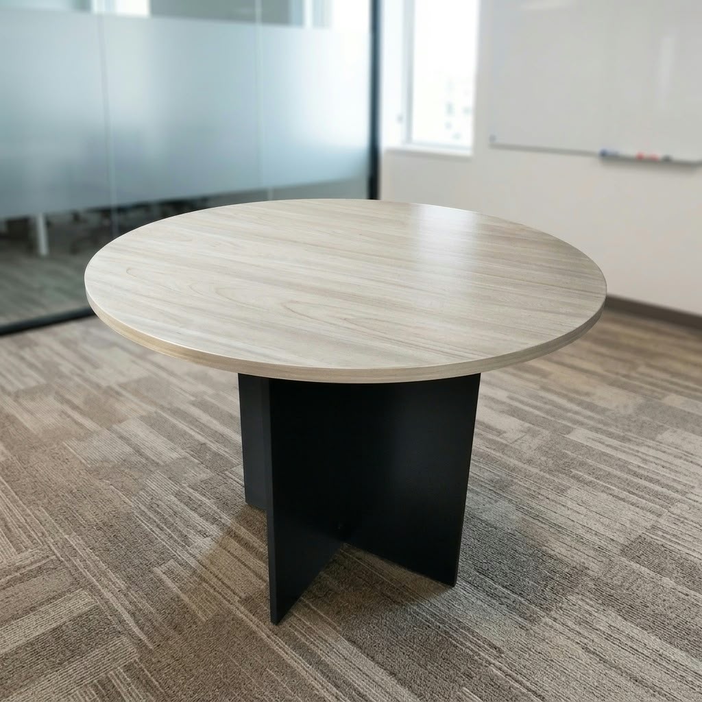 Modern Circular Executive Meeting Table with light oak round tabletop and black cross-panel base in a bright corporate office setting.