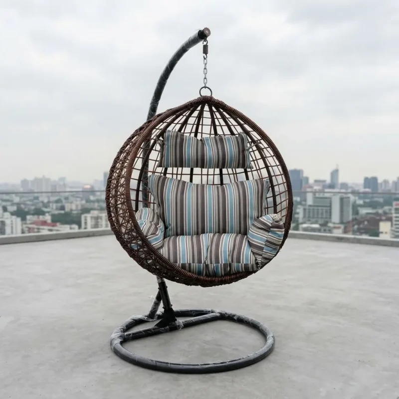Luxury Hanging Egg Swing Chair with dark brown wicker basket, heavy-duty steel stand, and blue striped cushions on a modern tiled office patio.